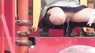 Naughty Japanese coed is peeing on a playground, while it's raining